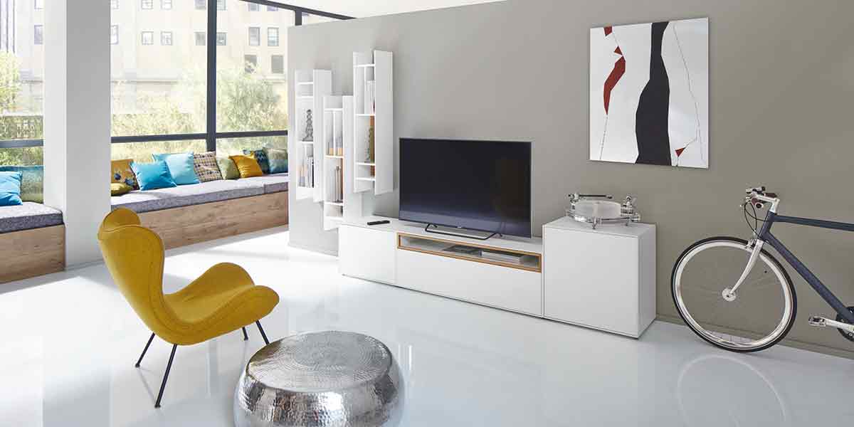 Titelbild Wohnzimmer Milieubild eines modernen Wohnzimmers. Im Fokus ist die Wohnwand, die aus einem Lowboard und drei hochkant aufgehängten Hängeregalen besteht.